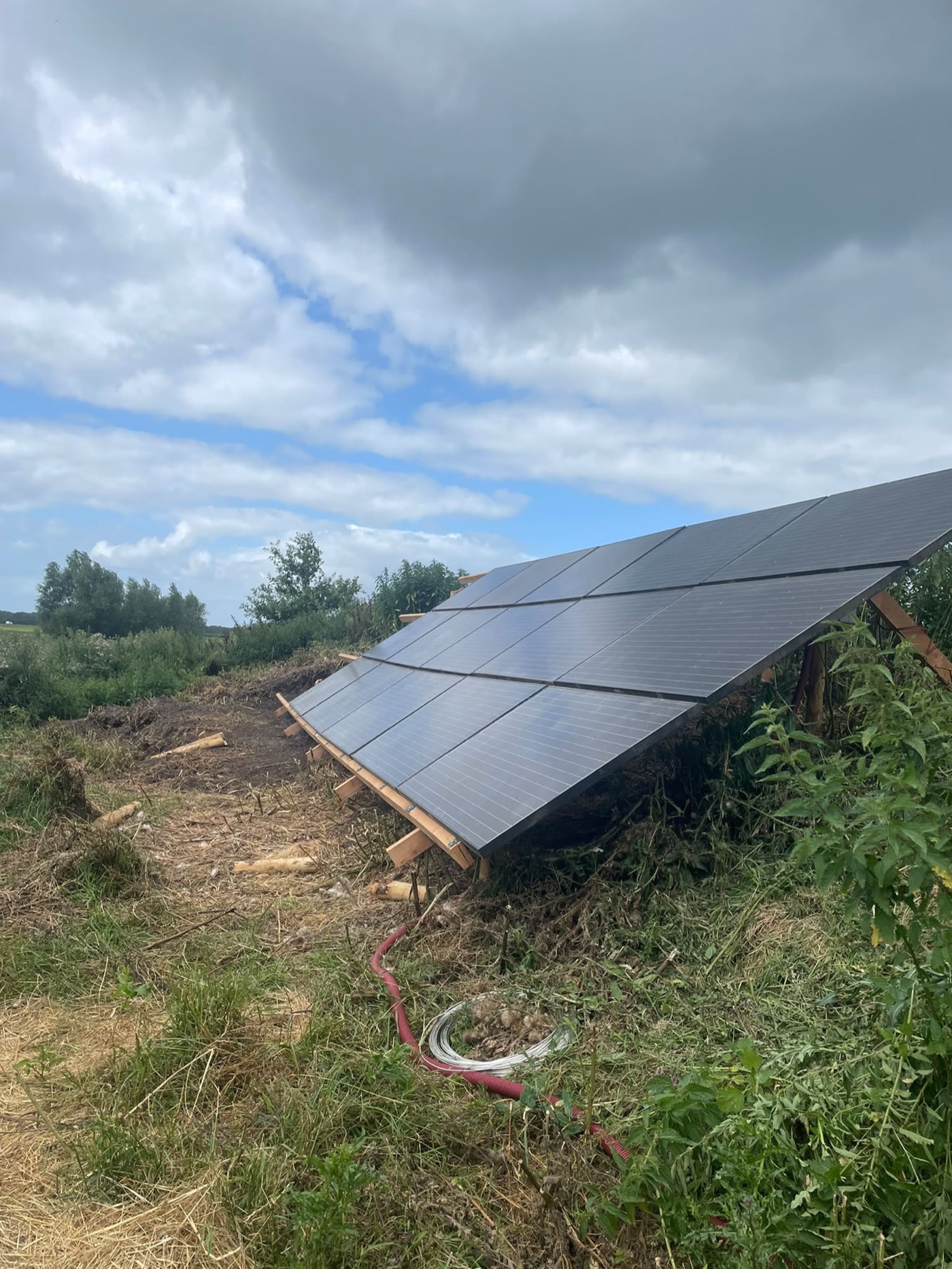 De zonnepanelen op het erf, in aanbouw tussen het groen
